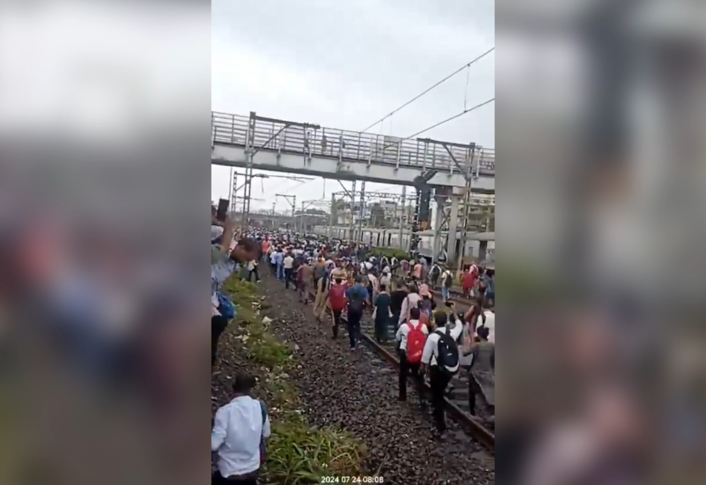 Commuters walk on railway tracks in western India after bamboo structure causes train disruption